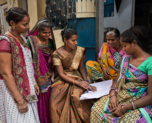 Five women gather outside their homes in Gujarat, India to discuss the area's upkeep and work issues
