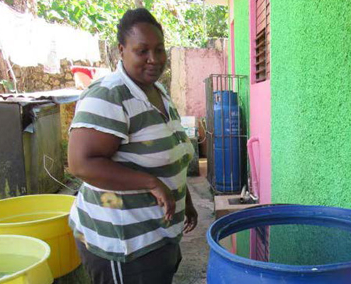 A woman outdoors near tubs of liquid in Jamaica