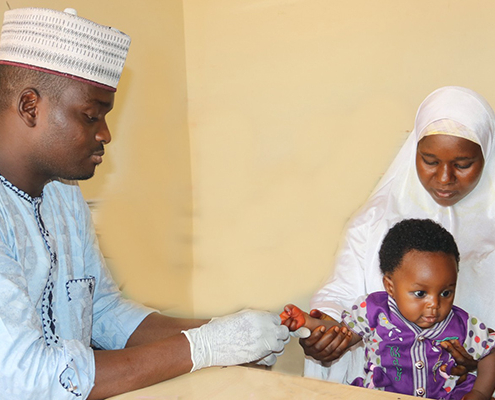 A health care provider tests a young child for malaria
