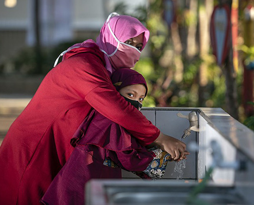 A mother helps her daughter wash her hands in Indonesia