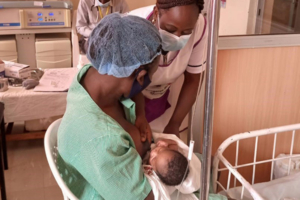 Nurse helping a mother breastfeed a newborn