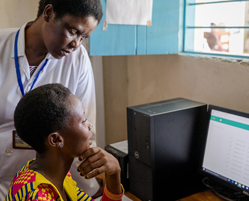 Staff at a dispensary in Tanzania speak with a woman to check her in as a new patient