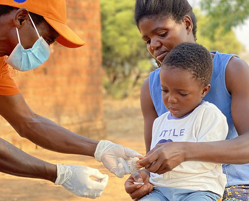 A community health worker uses a rapid malaria test on a young boy in Zambia