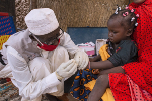 A community health worker performs a malaria rapid diagnostic test on a sick child