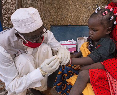 A community health worker performs a malaria rapid diagnostic test on a sick child