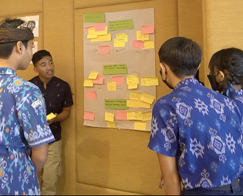 Four young adults gather around a poster board covered in post-it notes