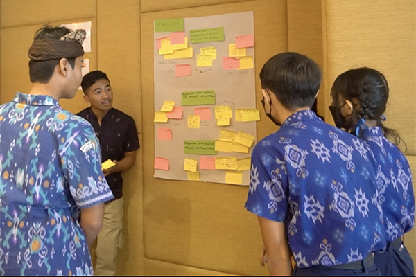 Four young adults gather around a poster board covered in post-it notes