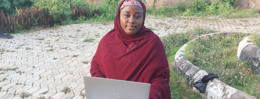 Breakthrough ACTION program officer works on a laptop in Nigeria
