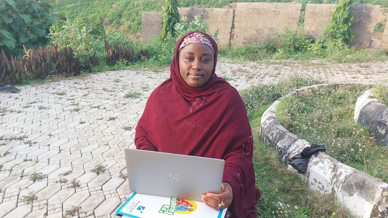 Breakthrough ACTION program officer works on a laptop in Nigeria