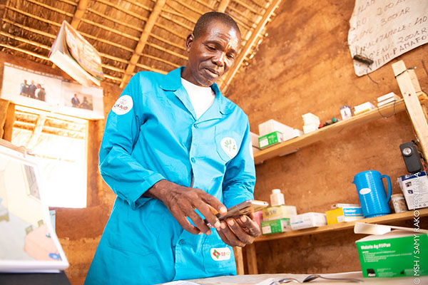 A male community health volunteer in Madagascar enters health data through a mobile application