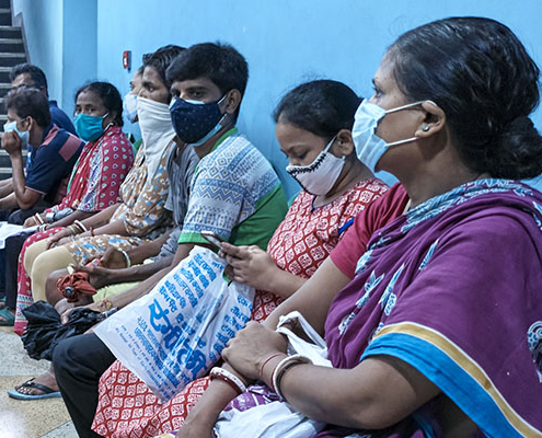 People wearing face masks waiting inside an auditorium to get the COVID-19 vaccine for free