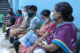 People wearing face masks waiting inside an auditorium to get the COVID-19 vaccine for free