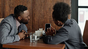 Two people sitting in café looking at a phone together