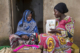 Female community health worker talks to a woman during a home visit in Uganda
