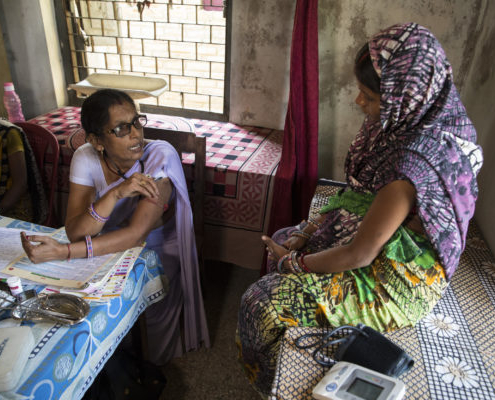 A nurse midwife talks to a patient at a health center in India