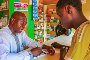 Male medicine vendor speaks with a young man in Nigeria