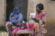 Female community health worker talks to a woman during a home visit in Uganda