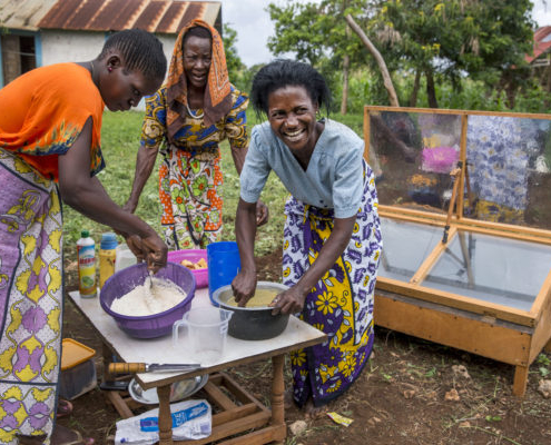 Three women preparing to bake cakes with a solar oven in Kenya