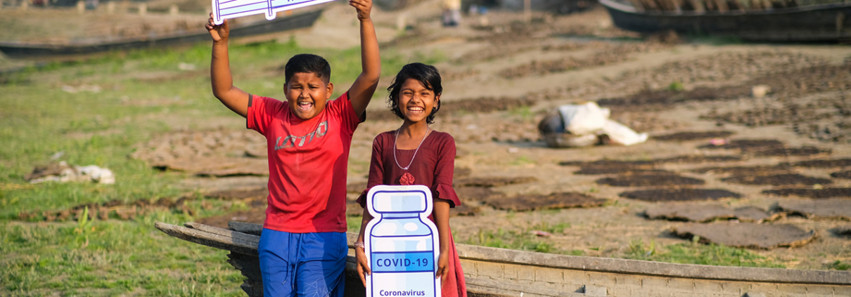 A 13 year old boy and 12 year old girl with signs about getting the COVID-19 vaccine in Bangladesh