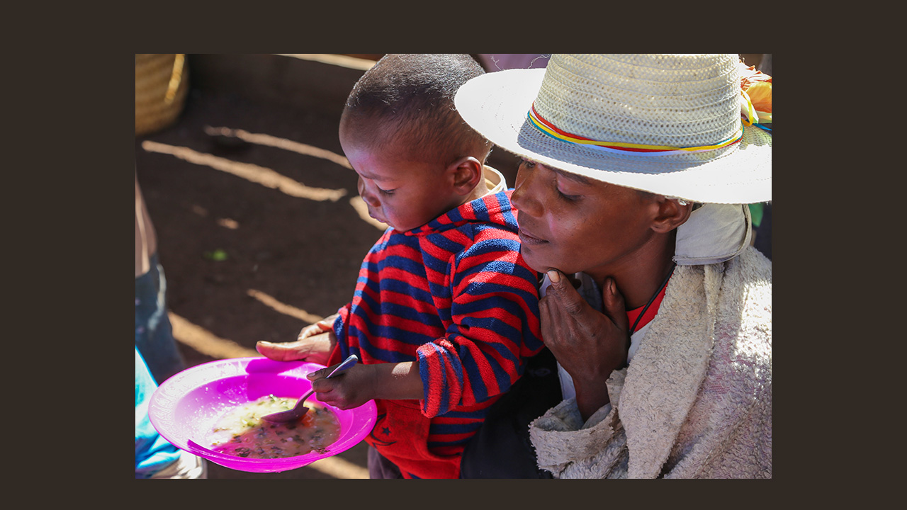 Mother holding bowl for child to eat from