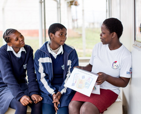 A female mentor provides health education to two adolescent women in the Kingdom of Eswatini