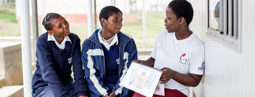 A female mentor provides health education to two adolescent women in the Kingdom of Eswatini