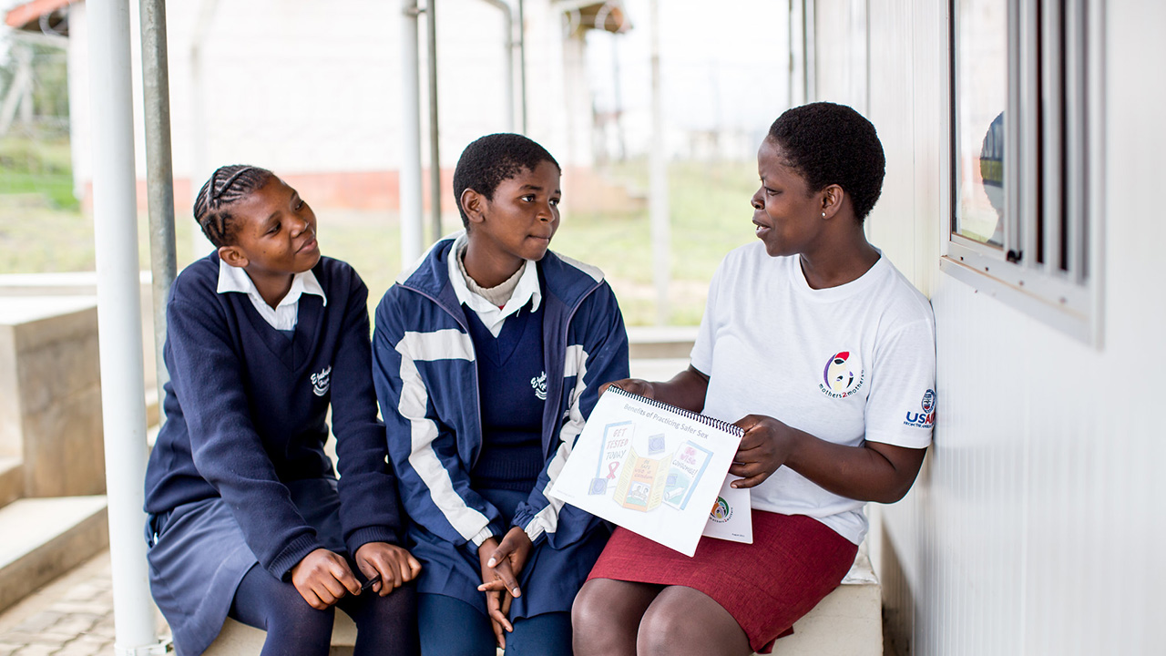 A female mentor provides health education to two adolescent women in the Kingdom of Eswatini