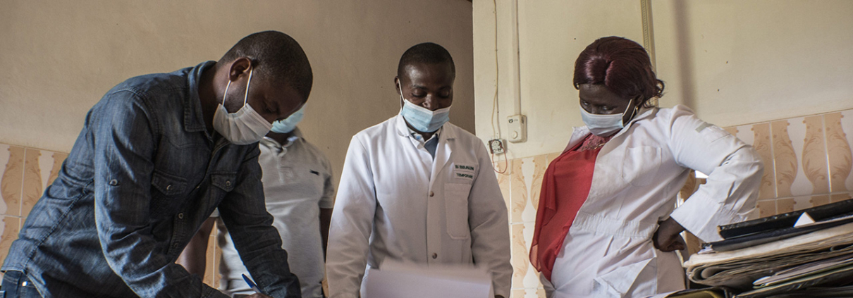 Four health providers in Sud Kivu, DRC, stand around a desk looking over papers