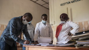 Four health providers in Sud Kivu, DRC, stand around a desk looking over papers