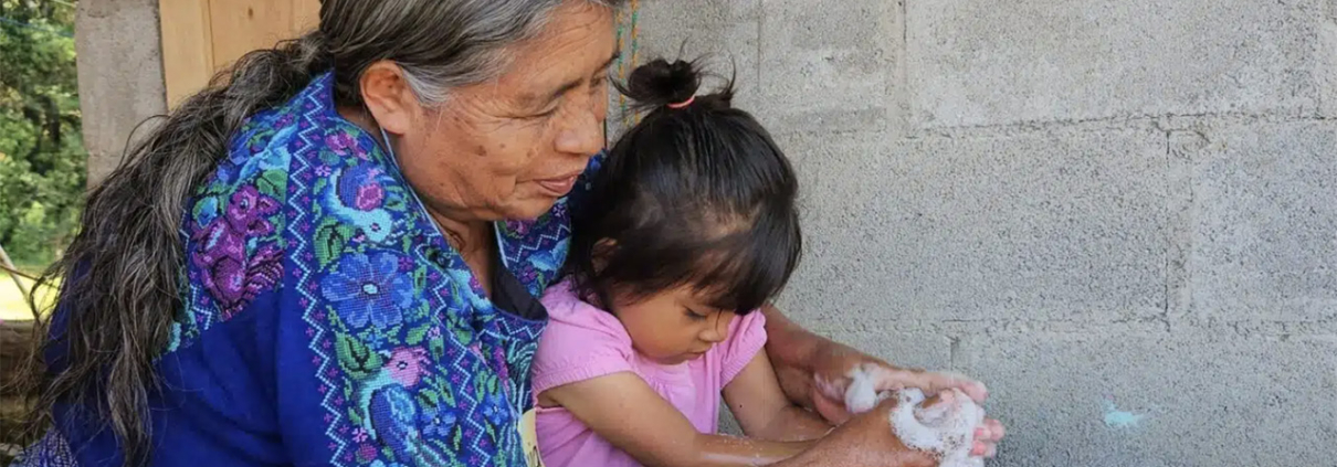 A Guatemalan grandmother washes the hands of her grandchild