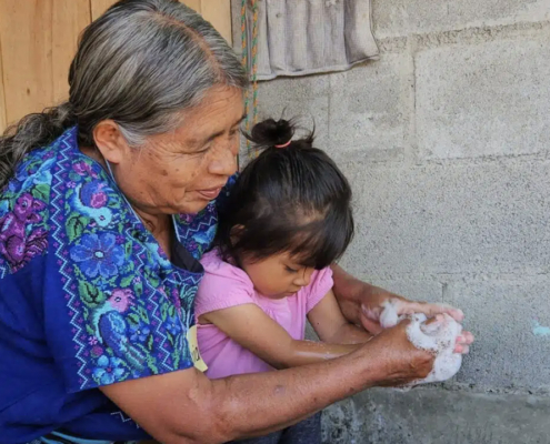 A Guatemalan grandmother washes the hands of her grandchild