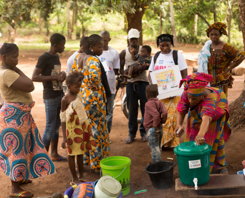 Plusieurs personnes se rassemblent autour d'un stand de lavage de l'USAID dans le cadre d'une campagne visant à débarrasser la Guinée d'Ebola