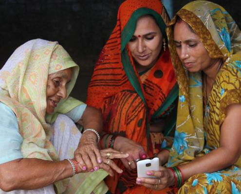 Three Indian women looking at a smartphone