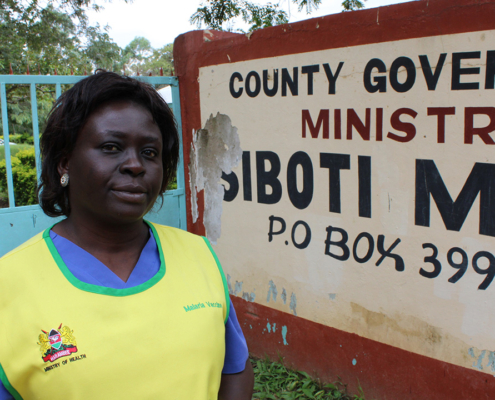 Ministry of Health worker stands in front of sign