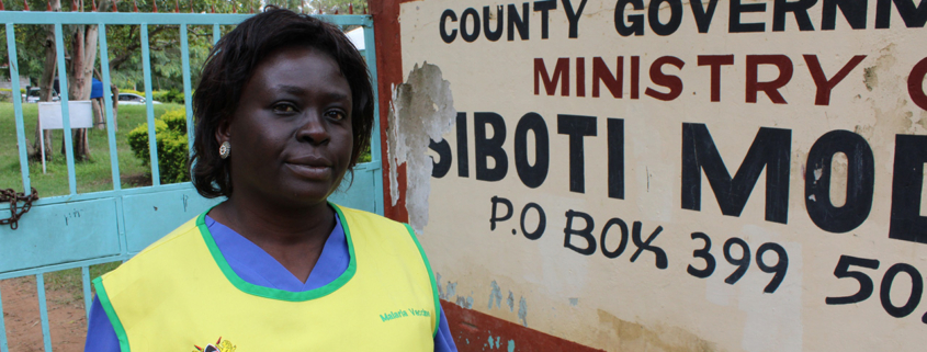 Ministry of Health worker stands in front of sign