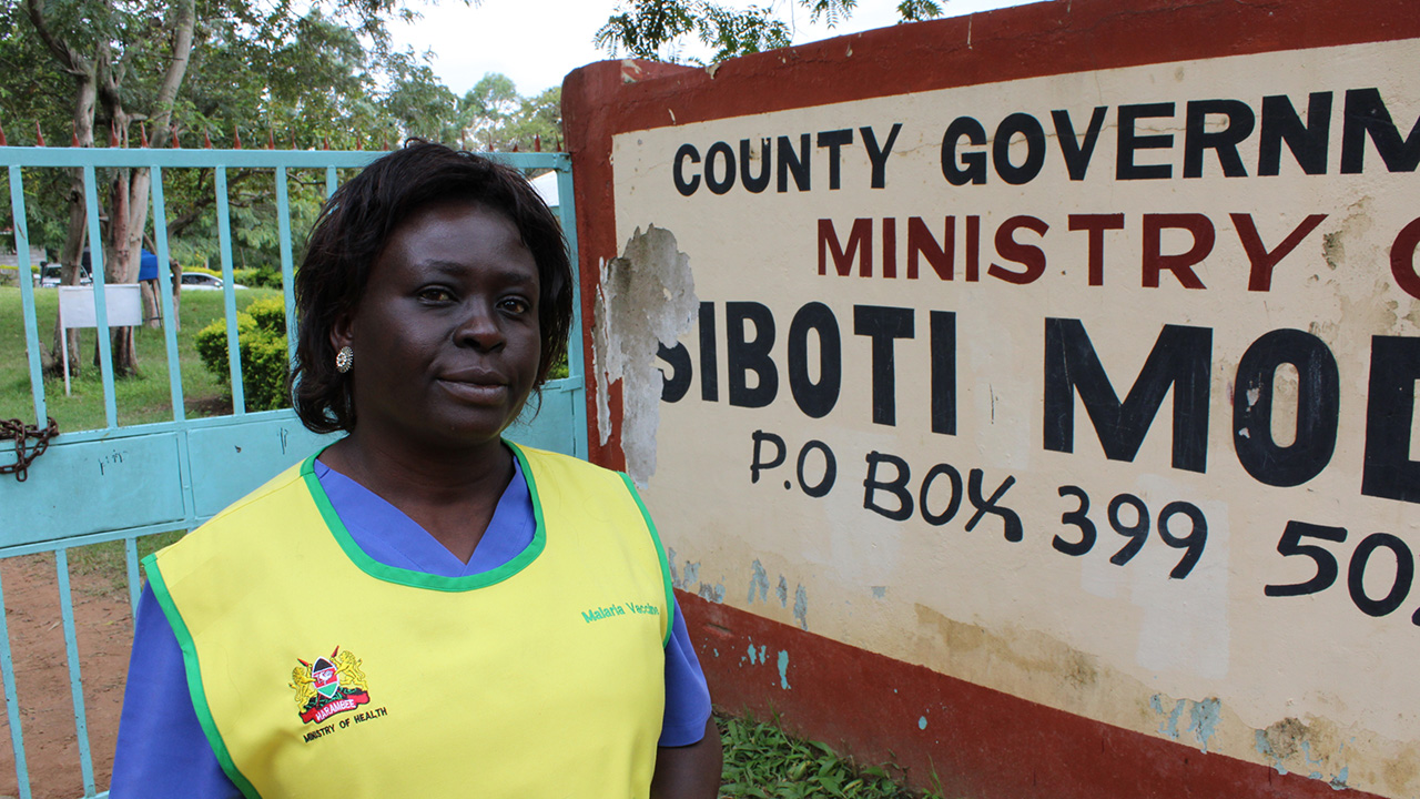 Ministry of Health worker stands in front of sign