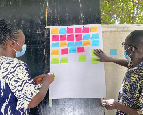 A woman and a man work with post-it notes during an HCD workshop in Kenya