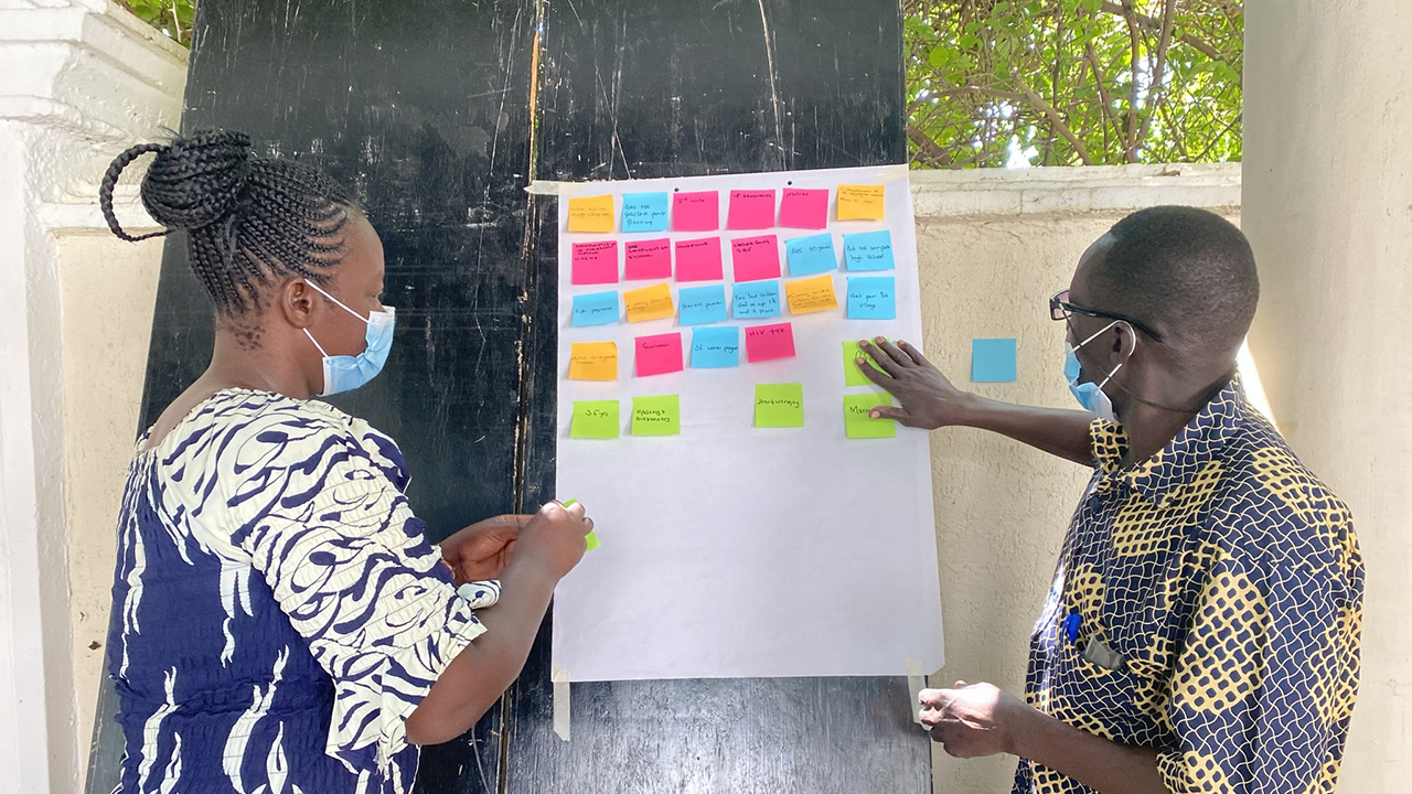 A woman and a man work with post-it notes during an HCD workshop in Kenya