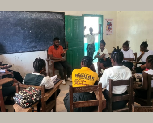 A group of Liberian students sitting in a circle in a classroom for a school health club meeting.