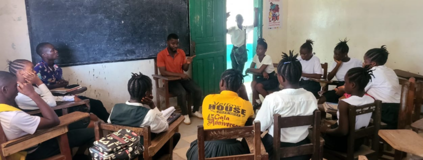 A group of Liberian students sitting in a circle in a classroom for a school health club meeting.