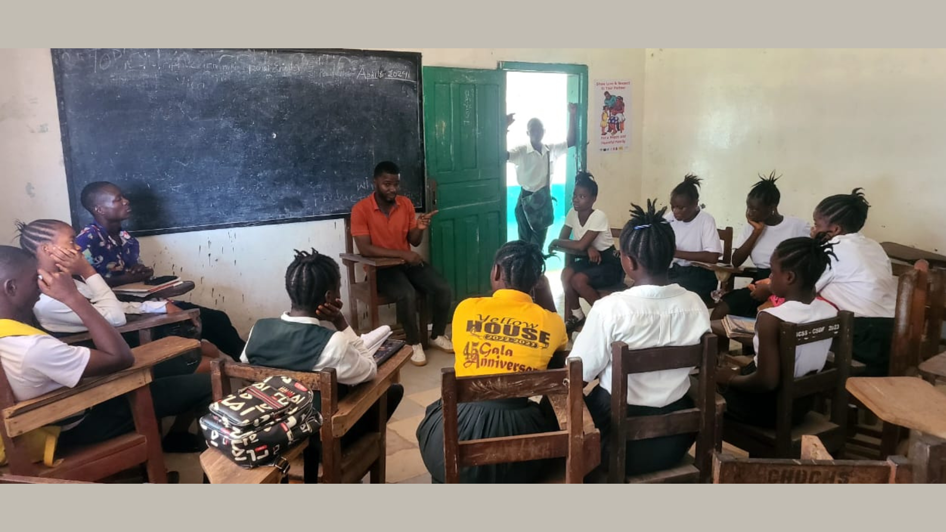 A group of Liberian students sitting in a circle in a classroom for a school health club meeting.