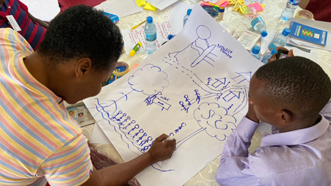 Two young men drawing during an HCD workshop in Tanzania