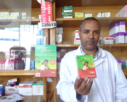 A private pharmacy staff member in Ethiopia holds a pack of Lem Lem Plus