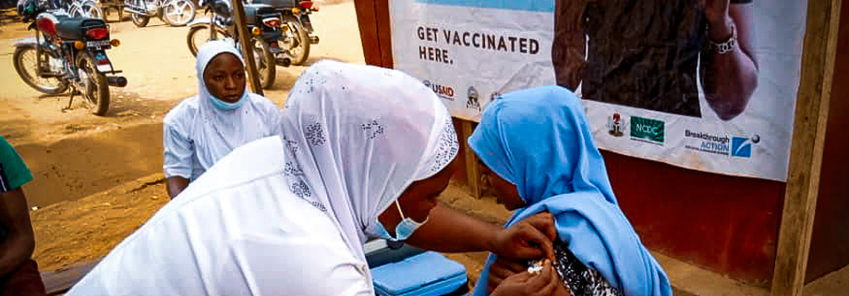 A woman receiving the COVID-19 vaccine from a community pharmacist