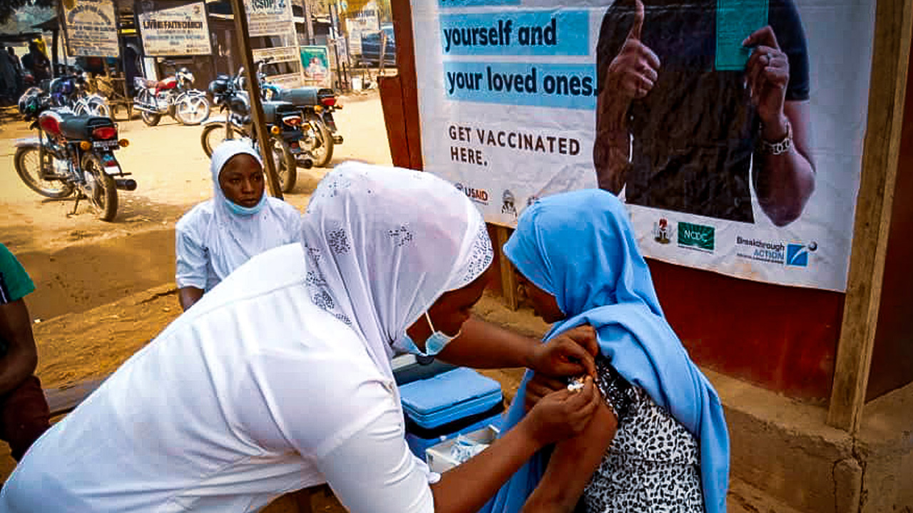 A woman receiving the COVID-19 vaccine from a community pharmacist