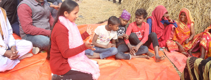 Young girl in Nepal speaking to a group of people during a community meeting.
