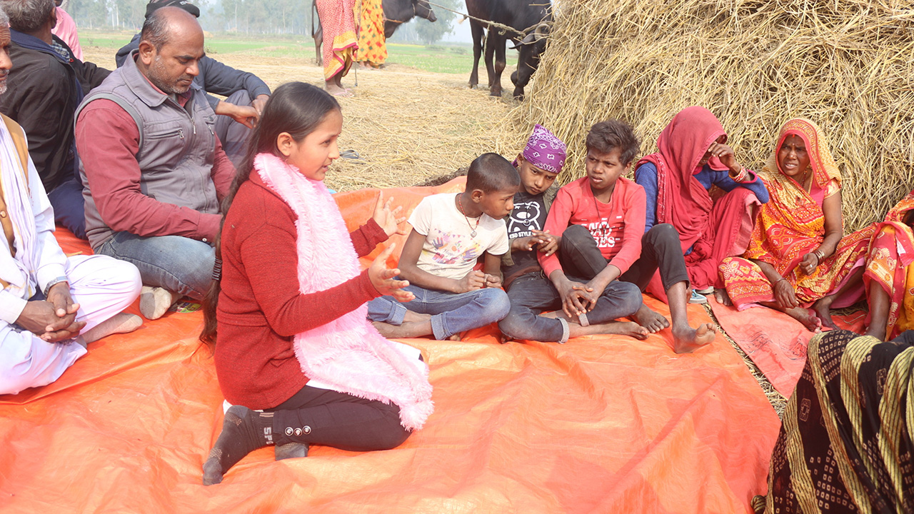 Young girl in Nepal speaking to a group of people during a community meeting.