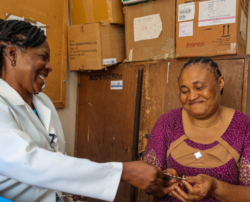 A female health care worker administers antimalarial treatment to her patient.