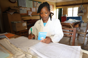 A female health care worker in a health clinic in Nigeria examines a patient register.