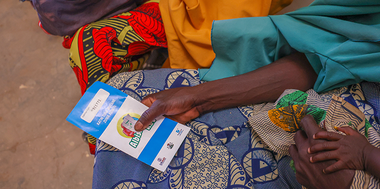 Closeup of a woman holding a Breakthrough ACTION referral card in Bui, Kebbi State, Nigeria